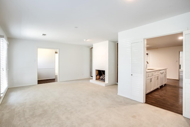 unfurnished living room with sink and light carpet