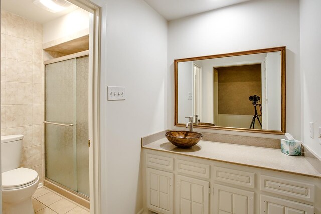 bathroom featuring tile patterned flooring, vanity, a shower with shower door, and toilet