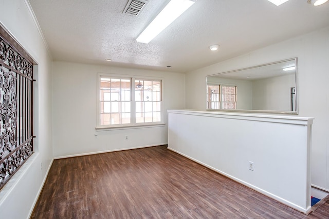 unfurnished room with dark hardwood / wood-style flooring and a textured ceiling