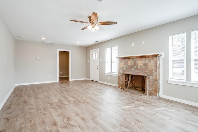 unfurnished living room with ceiling fan, a fireplace, and light wood-type flooring