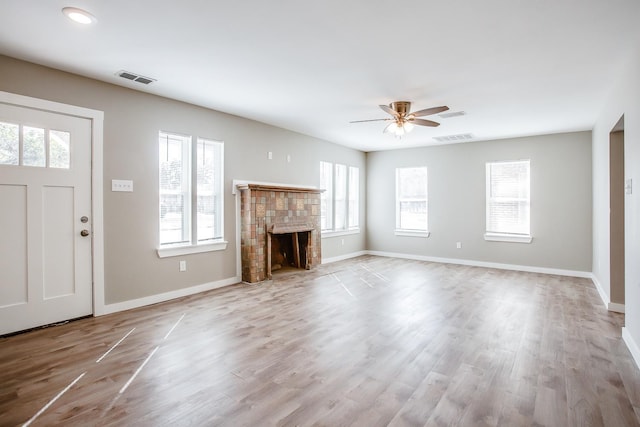 unfurnished living room featuring a tiled fireplace, light hardwood / wood-style flooring, and ceiling fan