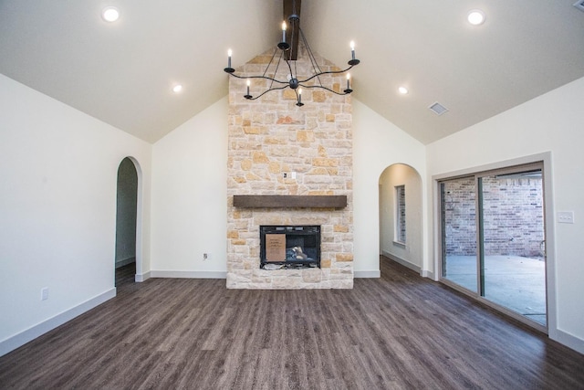 1312 Chaucer Ln, Wolfforth, TX 79382 - unfurnished living room with arched walkways, a chandelier, high vaulted ceiling, wood finished floors, and a stone fireplace