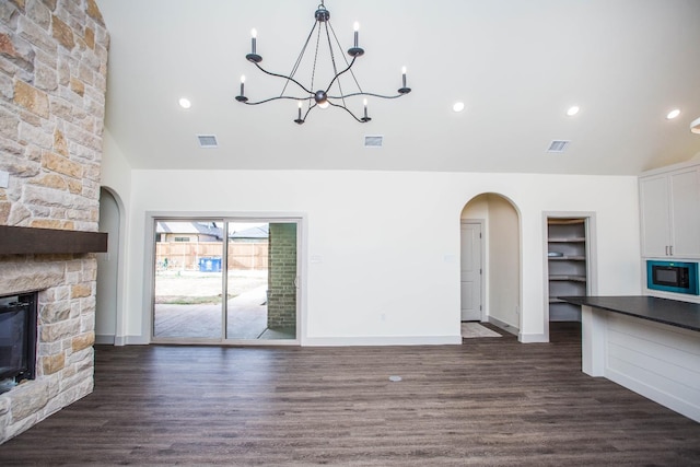 1312 Chaucer Ln, Wolfforth, TX 79382 - unfurnished living room with a fireplace, arched walkways, a chandelier, dark wood finished floors, and recessed lighting