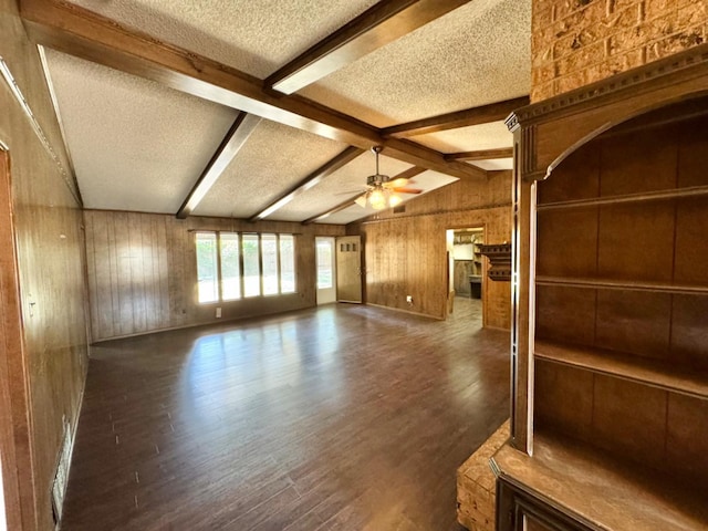 unfurnished living room with lofted ceiling with beams, a textured ceiling, wooden walls, dark hardwood / wood-style floors, and ceiling fan