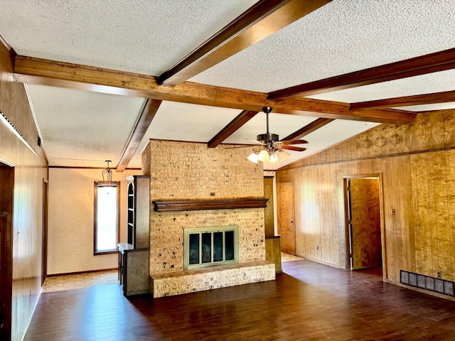 unfurnished living room featuring a brick fireplace, dark wood-type flooring, vaulted ceiling with beams, and a textured ceiling