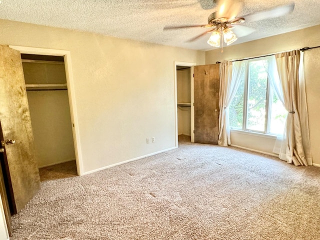 unfurnished bedroom with ceiling fan, a walk in closet, carpet, and a textured ceiling