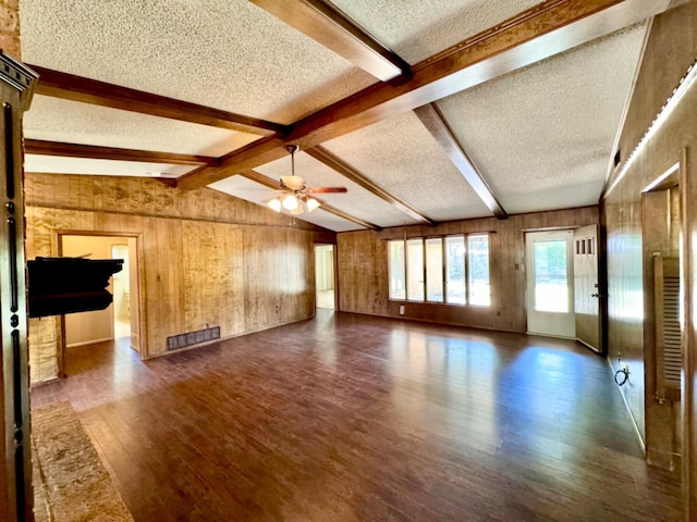 unfurnished living room with wood walls, vaulted ceiling with beams, ceiling fan, dark wood-type flooring, and a textured ceiling