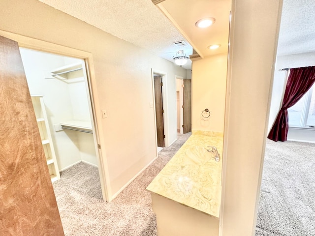 hallway featuring carpet flooring, sink, and a textured ceiling