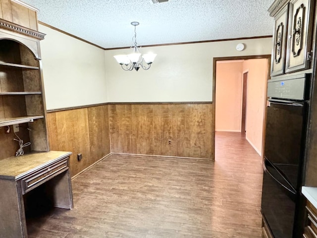 unfurnished dining area with hardwood / wood-style flooring, a textured ceiling, and wood walls