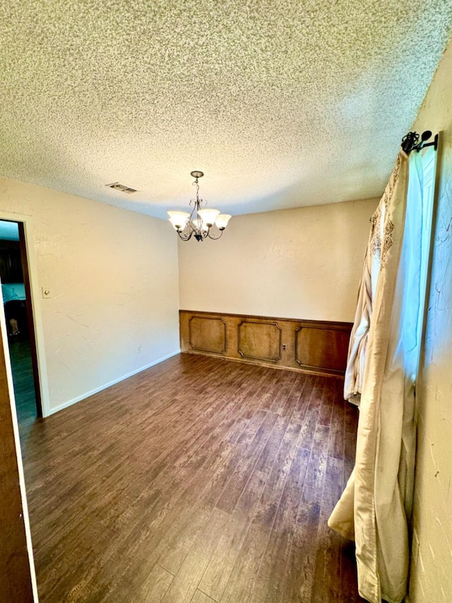 interior space with an inviting chandelier, dark hardwood / wood-style floors, and a textured ceiling