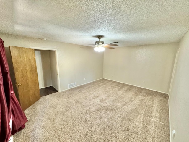 unfurnished room with a textured ceiling, ceiling fan, and carpet