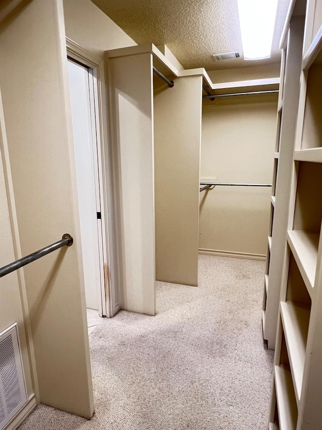 walk in closet with light colored carpet