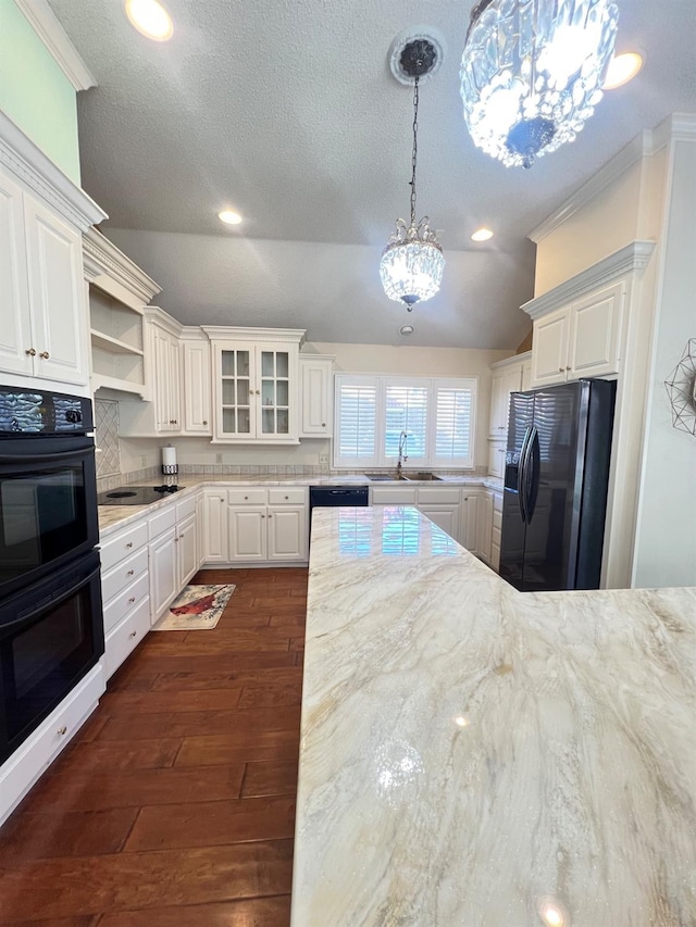 kitchen with pendant lighting, lofted ceiling, sink, white cabinets, and black appliances