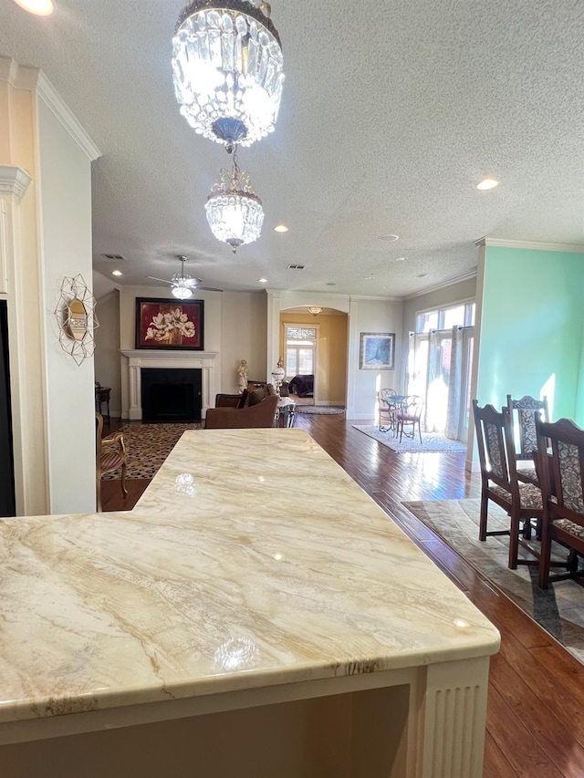 kitchen featuring ornamental molding, dark wood-type flooring, a textured ceiling, and decorative light fixtures