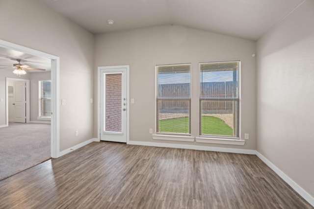 empty room featuring vaulted ceiling, plenty of natural light, and hardwood / wood-style floors