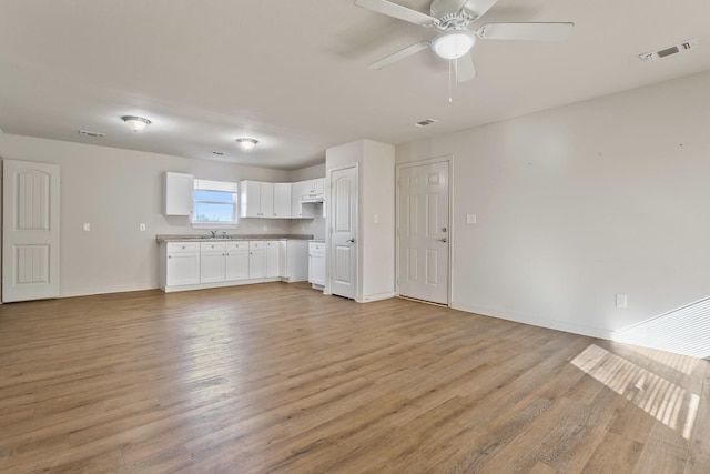 unfurnished living room with sink, light hardwood / wood-style flooring, and ceiling fan