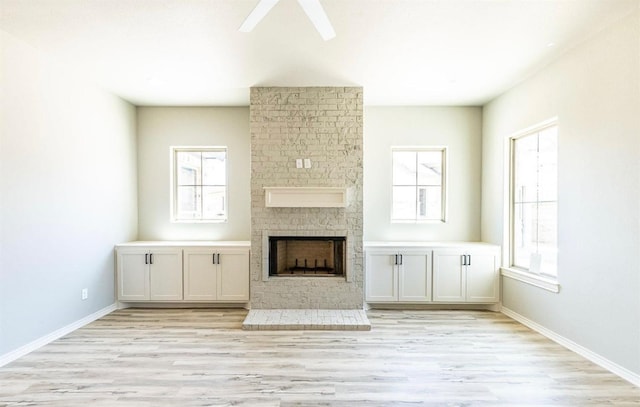 unfurnished living room featuring ceiling fan, a large fireplace, and light hardwood / wood-style floors