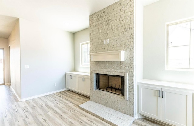 unfurnished living room with a brick fireplace and light hardwood / wood-style floors