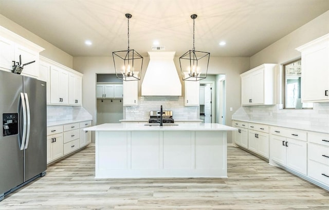 kitchen featuring stainless steel appliances, decorative light fixtures, custom exhaust hood, and white cabinets