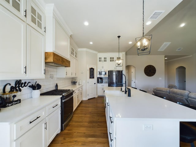 kitchen featuring appliances with stainless steel finishes, hanging light fixtures, a center island with sink, and white cabinets