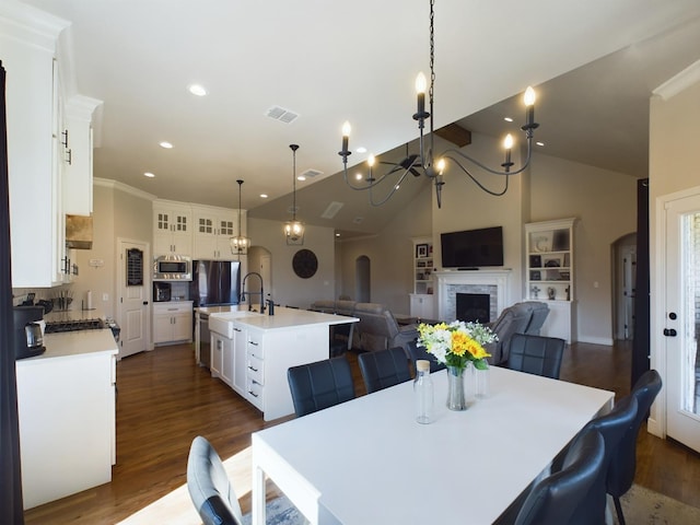 dining area with sink, a notable chandelier, dark wood-type flooring, and high vaulted ceiling