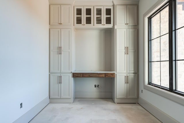 interior space featuring baseboards, concrete flooring, and built in study area