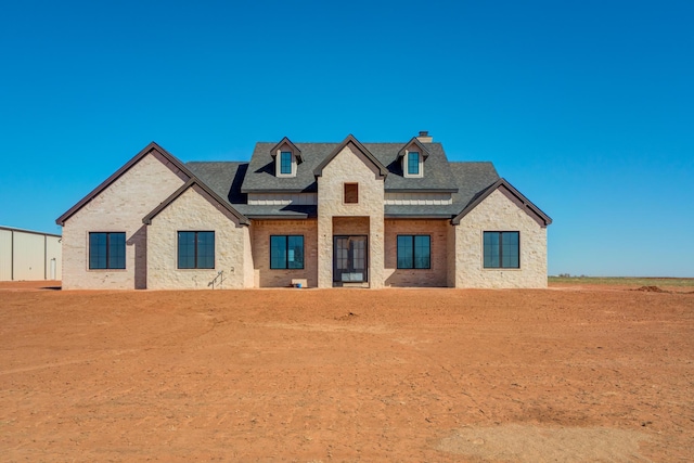 view of front facade with a standing seam roof, metal roof, brick siding, and a shingled roof