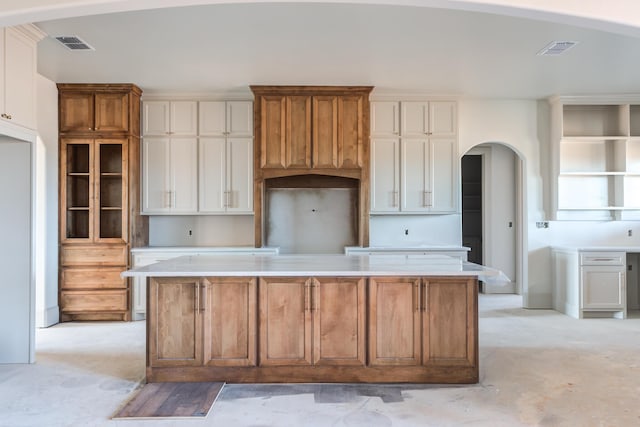 kitchen featuring white cabinets, arched walkways, visible vents, and a kitchen island