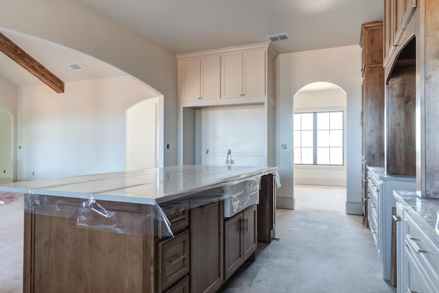 kitchen with visible vents, arched walkways, concrete floors, and light stone countertops