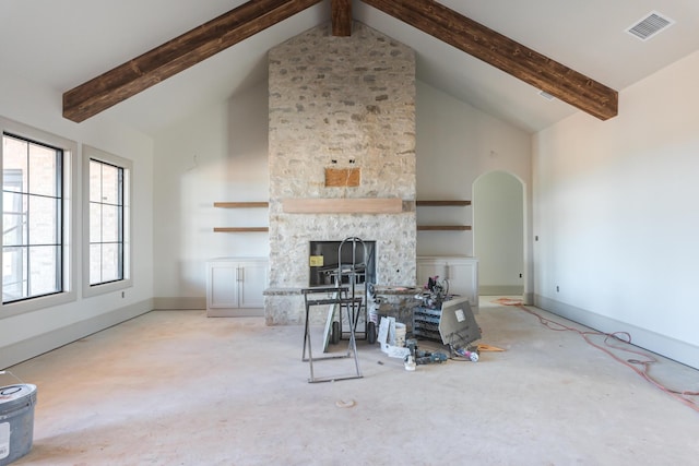 unfurnished living room with visible vents, beamed ceiling, high vaulted ceiling, a stone fireplace, and baseboards