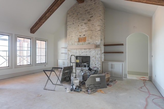 living area featuring baseboards, beamed ceiling, a stone fireplace, arched walkways, and high vaulted ceiling