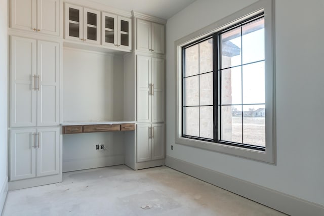 interior space featuring built in study area, concrete flooring, and baseboards