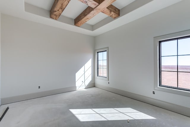 empty room with beamed ceiling, baseboards, and concrete flooring