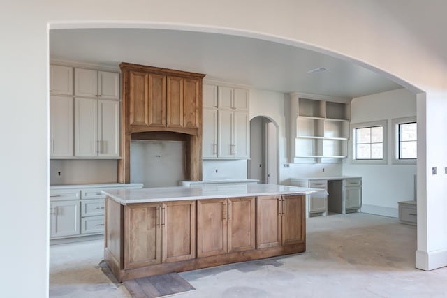 kitchen featuring arched walkways, concrete floors, and a center island