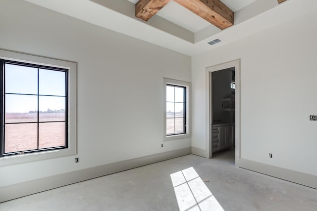 empty room with visible vents, beam ceiling, and baseboards