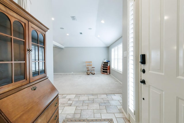 foyer with light carpet, baseboards, visible vents, and vaulted ceiling