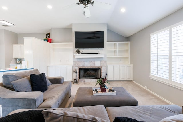 living area with baseboards, a ceiling fan, light colored carpet, lofted ceiling, and a tile fireplace