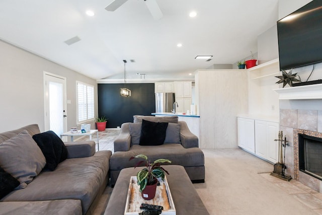 living room with ceiling fan, lofted ceiling, a fireplace, and light colored carpet