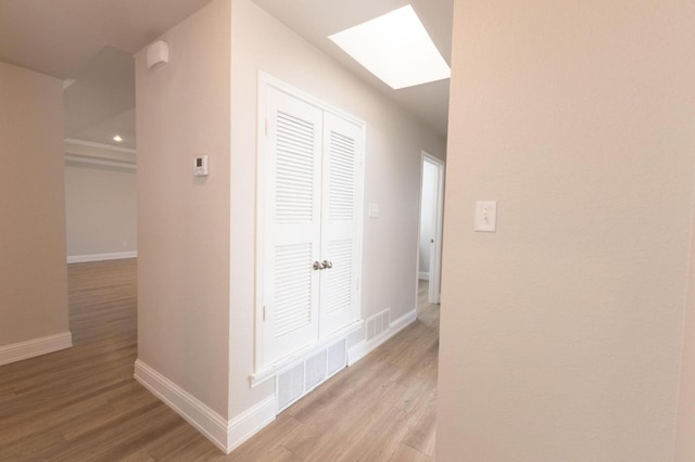 hall with light hardwood / wood-style flooring and a skylight