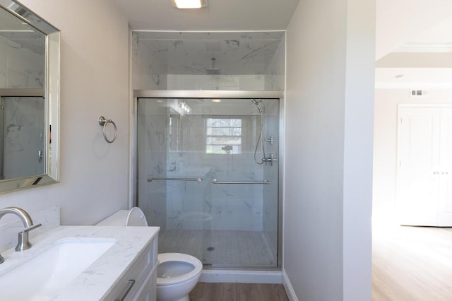 bathroom with vanity, hardwood / wood-style flooring, a shower with shower door, and toilet