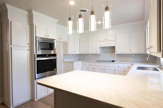 kitchen featuring appliances with stainless steel finishes, sink, white cabinets, backsplash, and hanging light fixtures