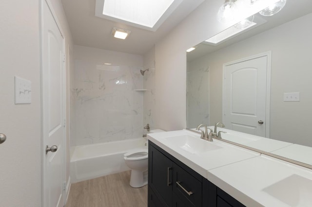 full bathroom featuring tiled shower / bath, hardwood / wood-style floors, a skylight, vanity, and toilet