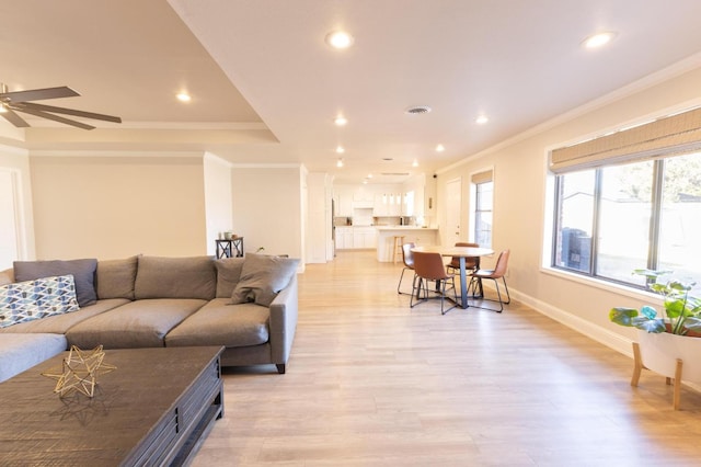 living room featuring ceiling fan, ornamental molding, and light wood-type flooring