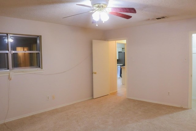 carpeted empty room with ceiling fan and a textured ceiling