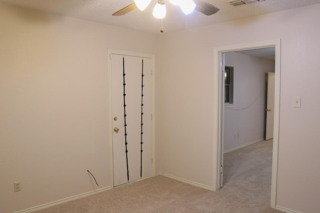 empty room featuring light carpet, a textured ceiling, and ceiling fan