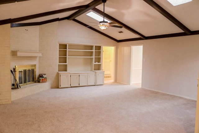 unfurnished living room with ceiling fan, light carpet, vaulted ceiling with skylight, and a fireplace