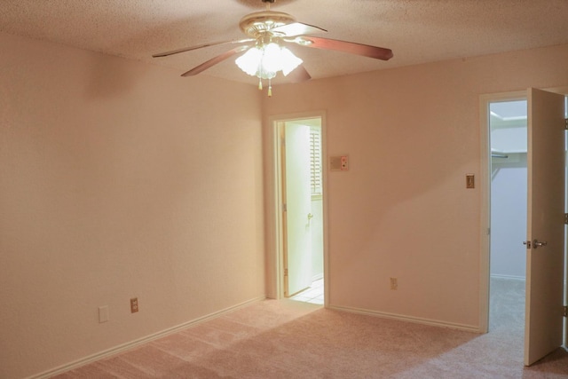 spare room featuring ceiling fan, light carpet, and a textured ceiling