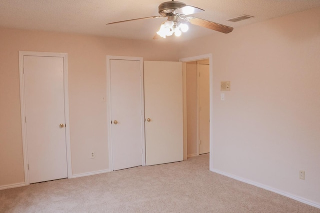 unfurnished bedroom featuring light carpet, ceiling fan, and a textured ceiling