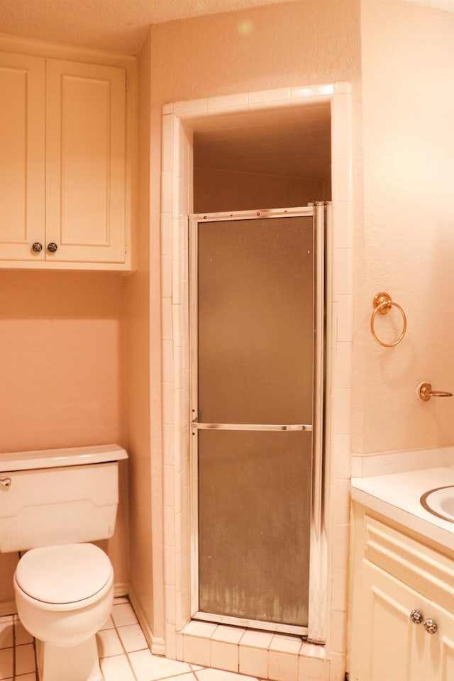 bathroom featuring a shower with door, vanity, tile patterned flooring, and toilet