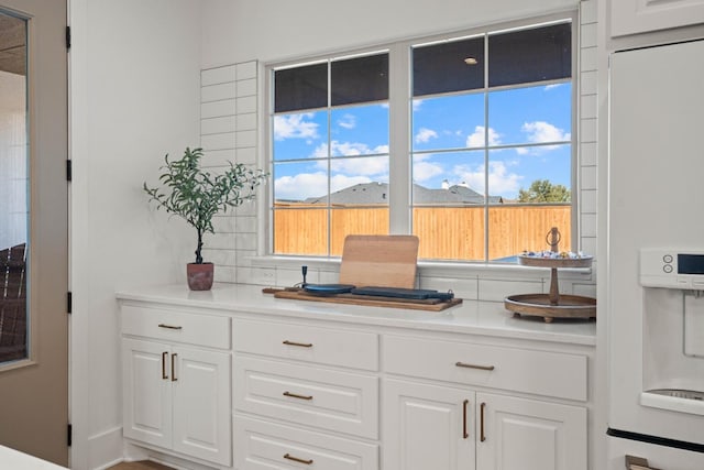 bar with a mountain view, backsplash, white fridge with ice dispenser, and white cabinets